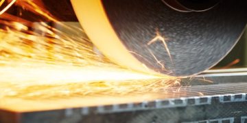 An industrial grinding wheel at work, sparks flying off to the side.