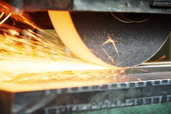 An industrial grinding wheel at work, sparks flying off to the side.