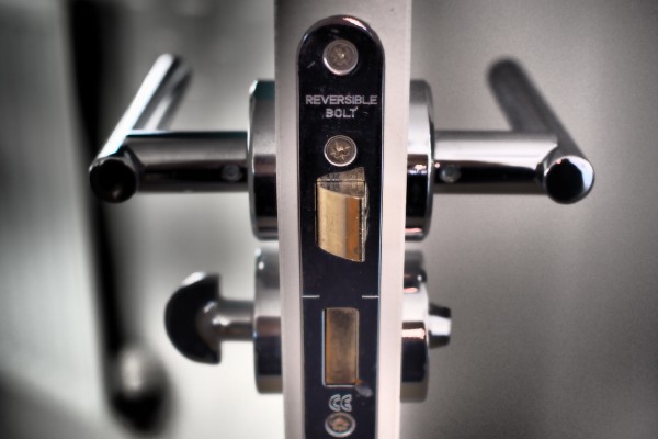 A modern entryway door that's open with the lock and handles front and center. The handles are stainless steel.