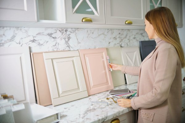 A female homeowner shopping for kitchen cabinets. The samples are pink and cream, with different door pulls.