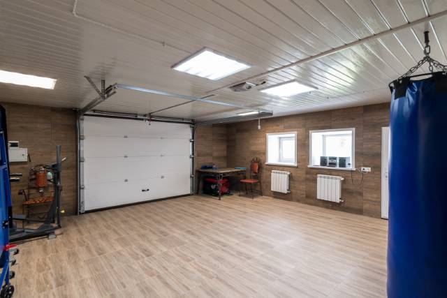 A residential garage with a white, overhead garage door. The space is empty aside from a punching bag, a table and chairs.