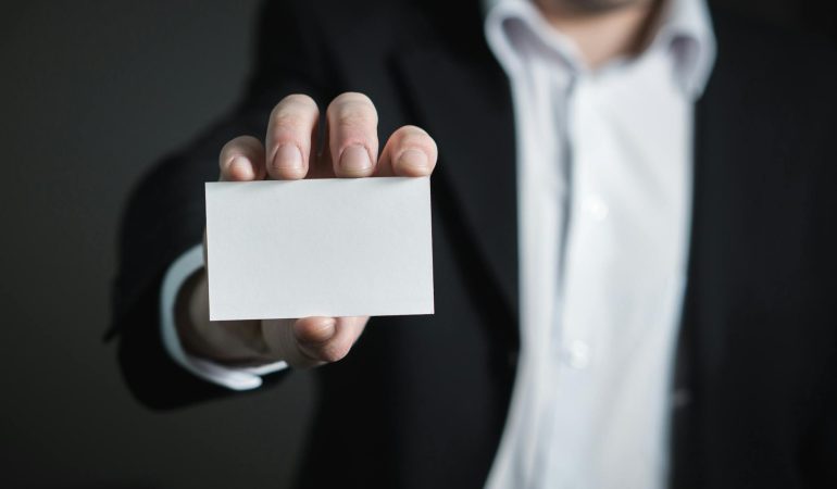 business cards close up of hand holding text over black background