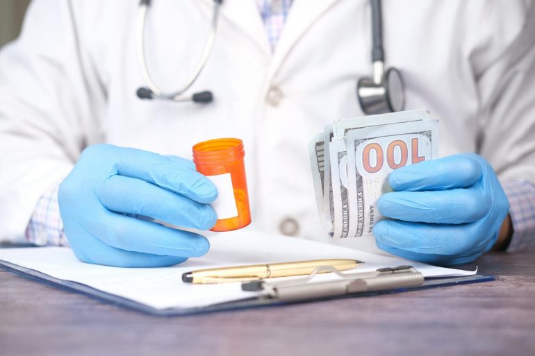 medical bills person holding money and pill bottle