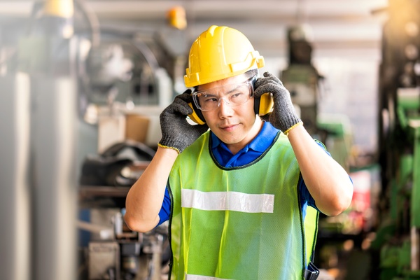 An industrial facility professional wearing a yellow safety vest, yellow hard hat, and clear safety glasses. Different types of metalworking eye protection