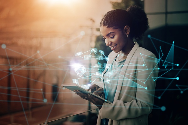 Blue interconnected digital networking lines are superimposed over a woman looking at a large tablet.