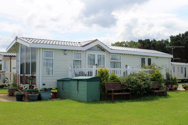 A modern mobile home in a quaint mobile home neighborhood. The outside of the mobile home is freshly landscaped.
