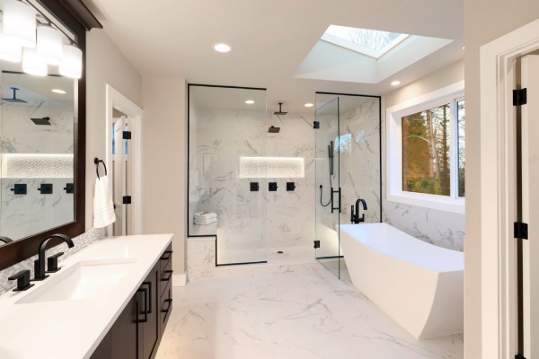 A luxurious bathroom with white wall, marble floors, black hardware, a large walk-in shower, a tub, and a large mirror.