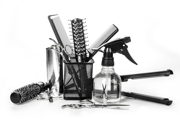 A chaotic assortment of hairstylist tools. Some of them are in a small basket, while others are laying around it.