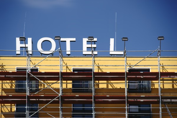 A building with the word "hotel" on its roof undergoes a renovation. It has scaffolding on its exterior.