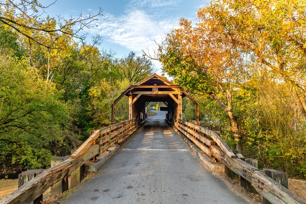 A covered bridge in Harrisburg, Tennessee. The end of fall has made some leaves yellow, but others are still green.